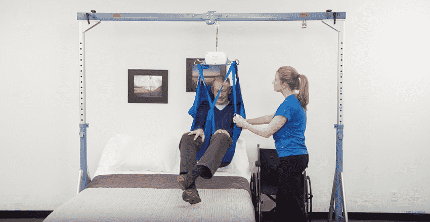 healthcare professional assisting man in a ceiling lift