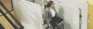executive woman on wheelchair smiling getting off vertical platform lift