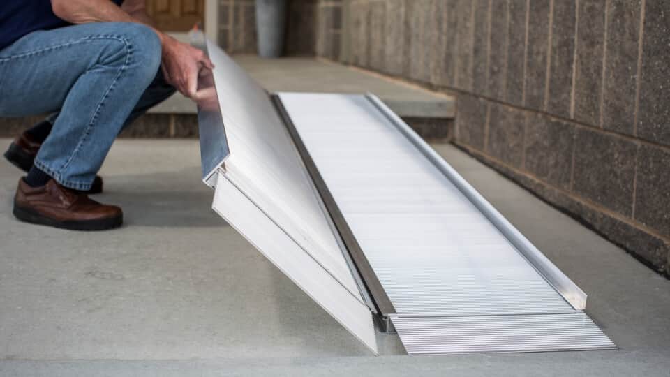 man adjusting portable ramps infront building