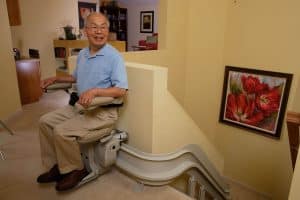 man at top of staircase using stair lift