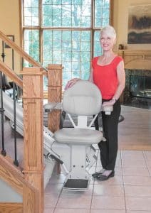 standing senior woman next to the stair lift at the bottom of stairs