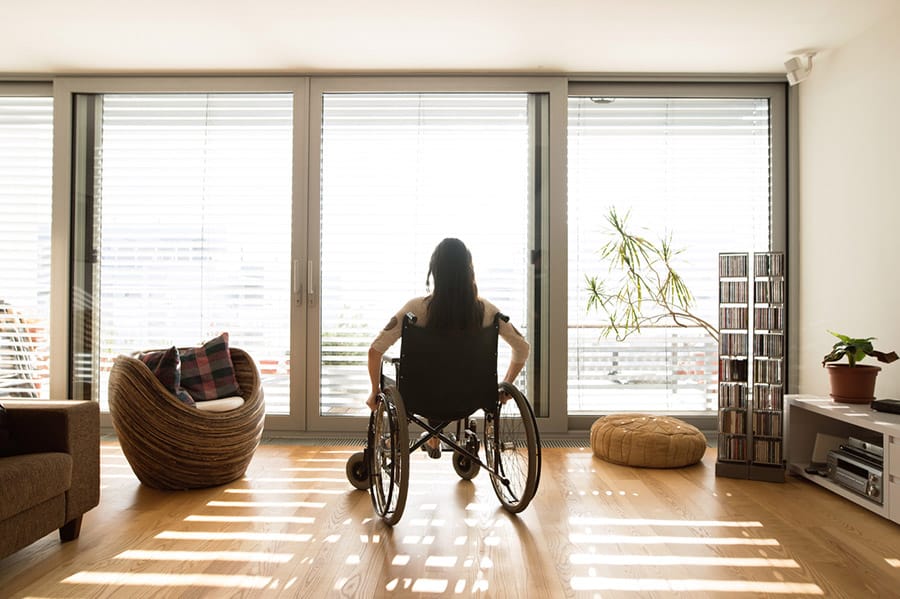 rear view of woman in wheelchair at home looking at window