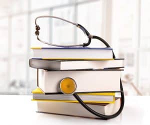 stack of books with stethoscope on the table in library