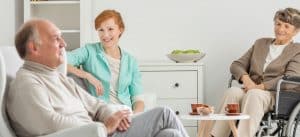 elderly couple talking with younger woman while senior woman is on wheelchair
