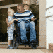 man in wheelchair with arms around stading child