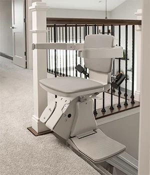 Straight indoor stair lift with a compact seat and slim rail on a residential staircase
